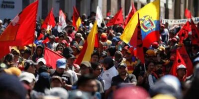 Una multitud con banderas rojas y de Ecuador durante una movilización en la calle.