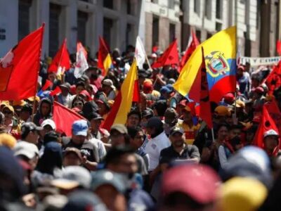 Una multitud con banderas rojas y de Ecuador durante una movilización en la calle.