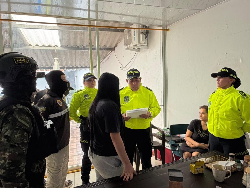 Agentes uniformados junto a dos mujeres en una habitación.