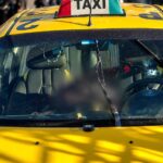 Taxi amarillo visto de frente, con parte de su interior difuminada.