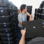 Distribución de kits electorales del CNE: un funcionario manipula una de las maletas de kits técnicos apiladas en una bodega, el 11 de octubre de 2026.