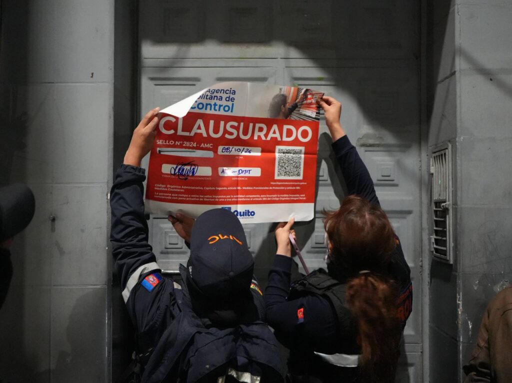 Personal de la Agencia Metropolitana de Control coloca un sello de clausura en la puerta de un establecimiento de Quito.