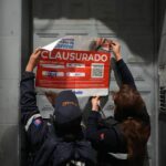 Personal de la Agencia Metropolitana de Control coloca un sello de clausura en la puerta de un establecimiento de Quito.