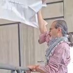 Santiago Rosano sostiene una pancarta junto a una barrera durante la protesta en la Universidad de Cuenca.