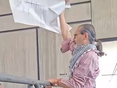 Santiago Rosano sostiene una pancarta junto a una barrera durante la protesta en la Universidad de Cuenca.