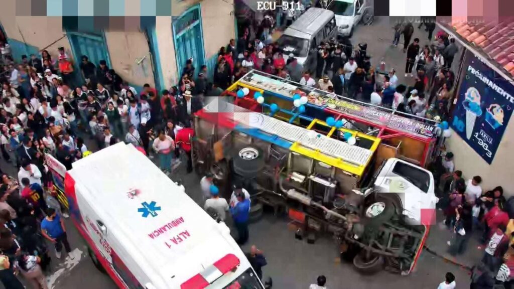 Un vehículo de transporte volcado en una calle, rodeado de personas y una ambulancia.