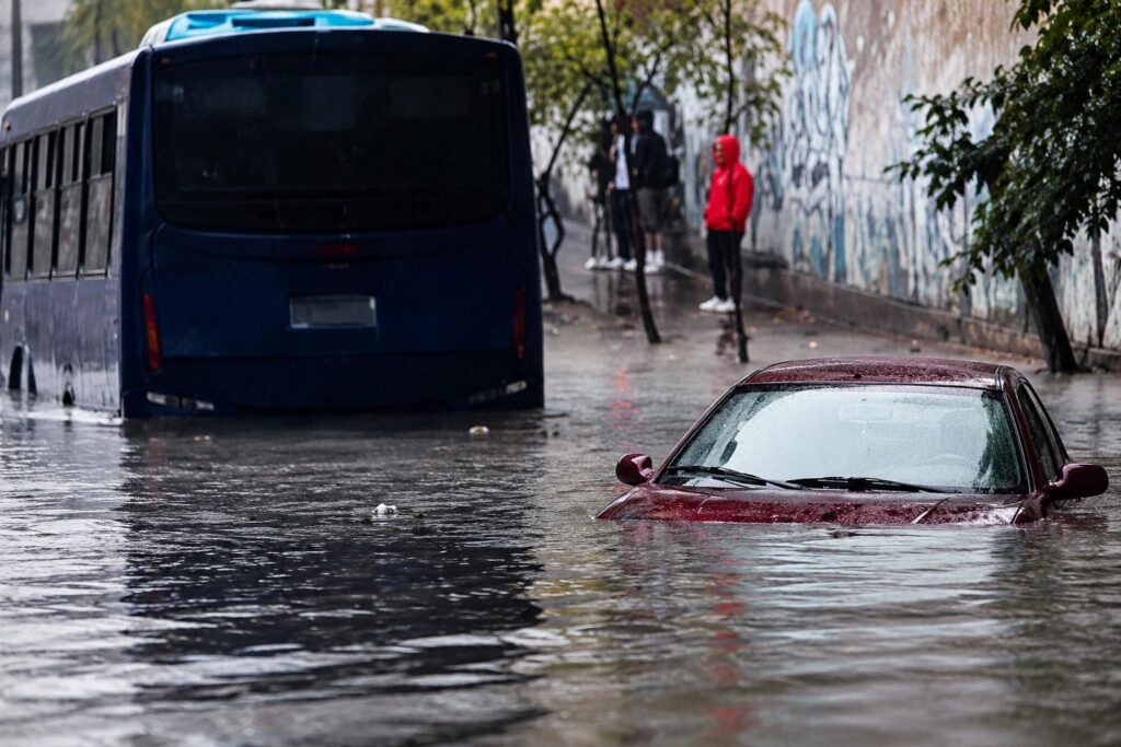 Un autobús y un automóvil en una calle cubierta por agua.