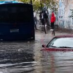 Un autobús y un automóvil en una calle cubierta por agua.