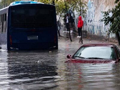 Un autobús y un automóvil en una calle cubierta por agua.