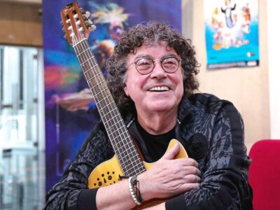 El cantante Piero sonríe mientras sostiene una guitarra durante una entrevista.
