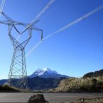 Torre de transmisión eléctrica con líneas de alta tensión frente a montañas.