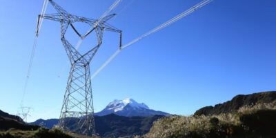 Torre de transmisión eléctrica con líneas de alta tensión frente a montañas.