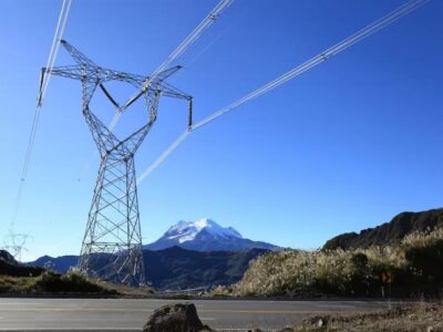 Torre de transmisión eléctrica con líneas de alta tensión frente a montañas.