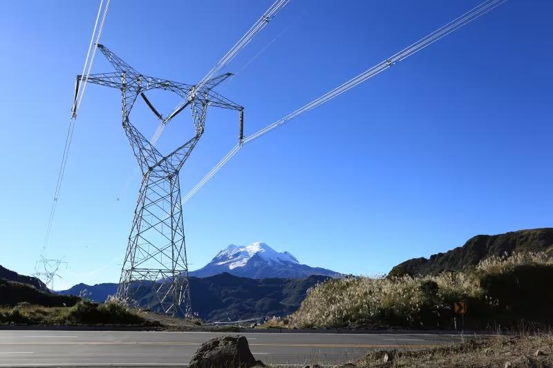 Torre de transmisión eléctrica con líneas de alta tensión frente a montañas.